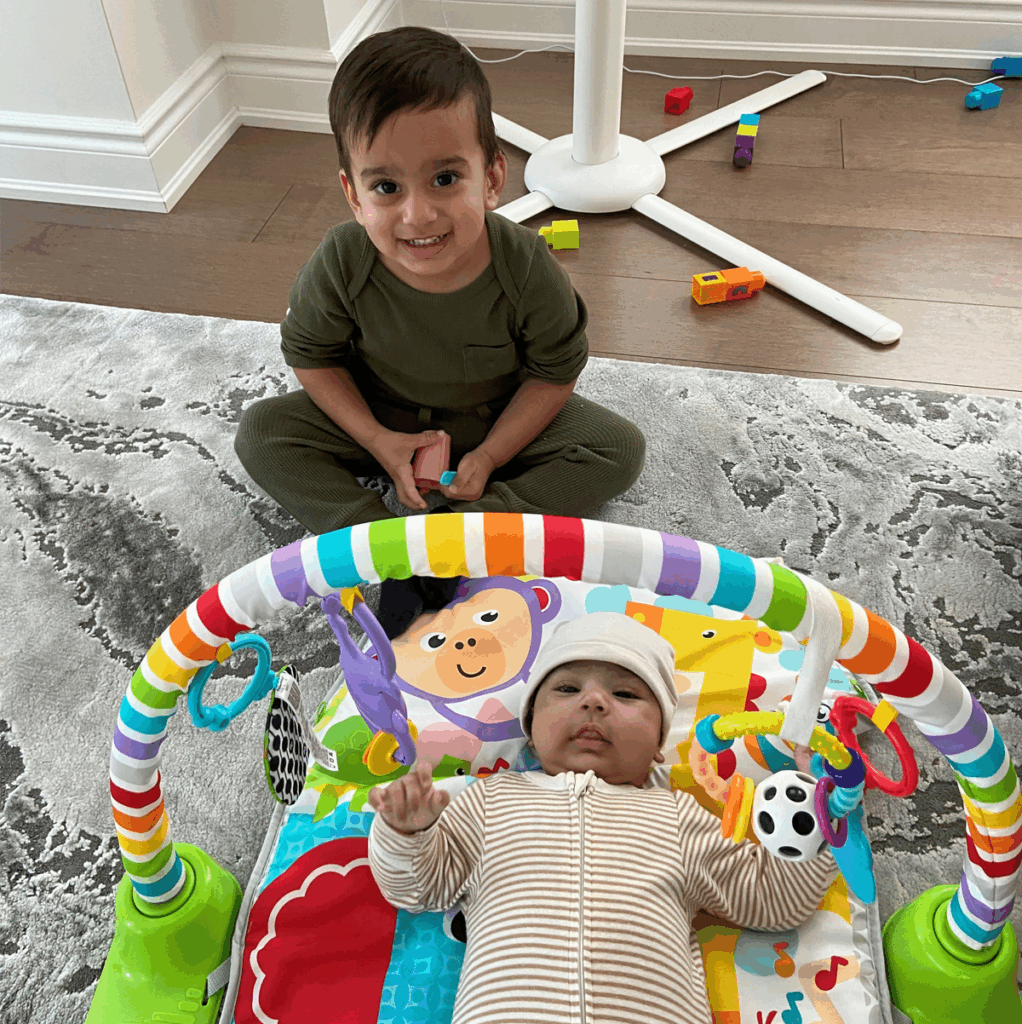 Image of a toddler and infant smiling up at the camera.