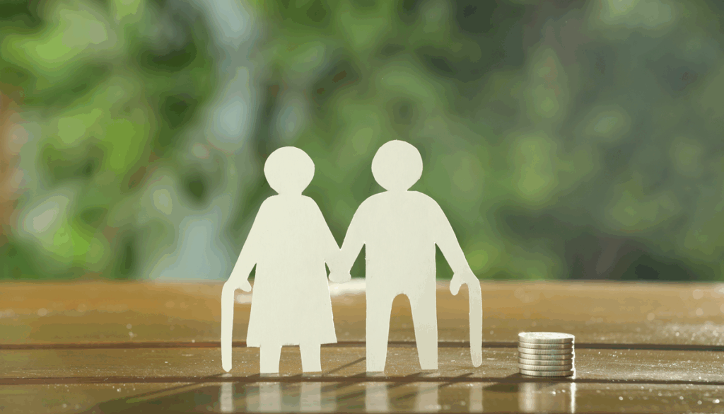 Image showing a paper cut out of an elderly couple holding hands. There is a stack of coins to the right of them.